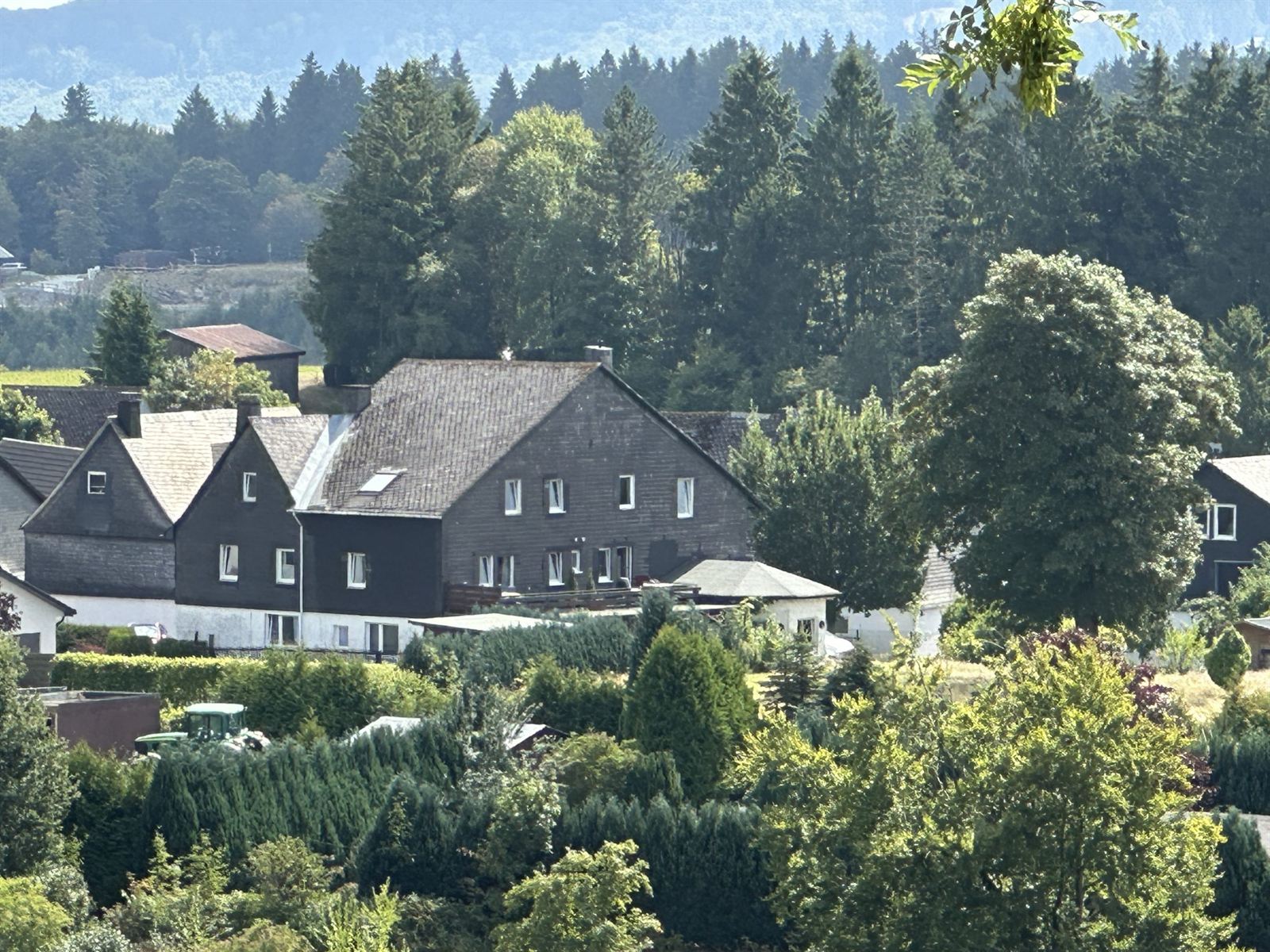 Blick über das Dorf und die grünen Wiesen und Hügel im Sommer
